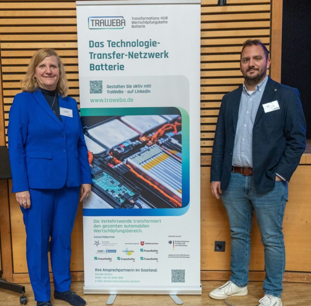 Zwei Teilnehmende stehen neben dem TraWeBa-Roll-up bei der Veranstaltung Gamechanger Batterie in Spiesen-Elversberg